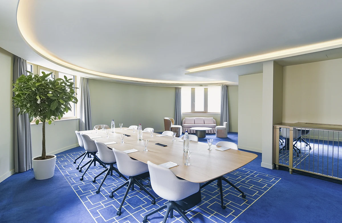Salle de réunion élégante avec mobilier en bois clair et équipements audiovisuels professionnels